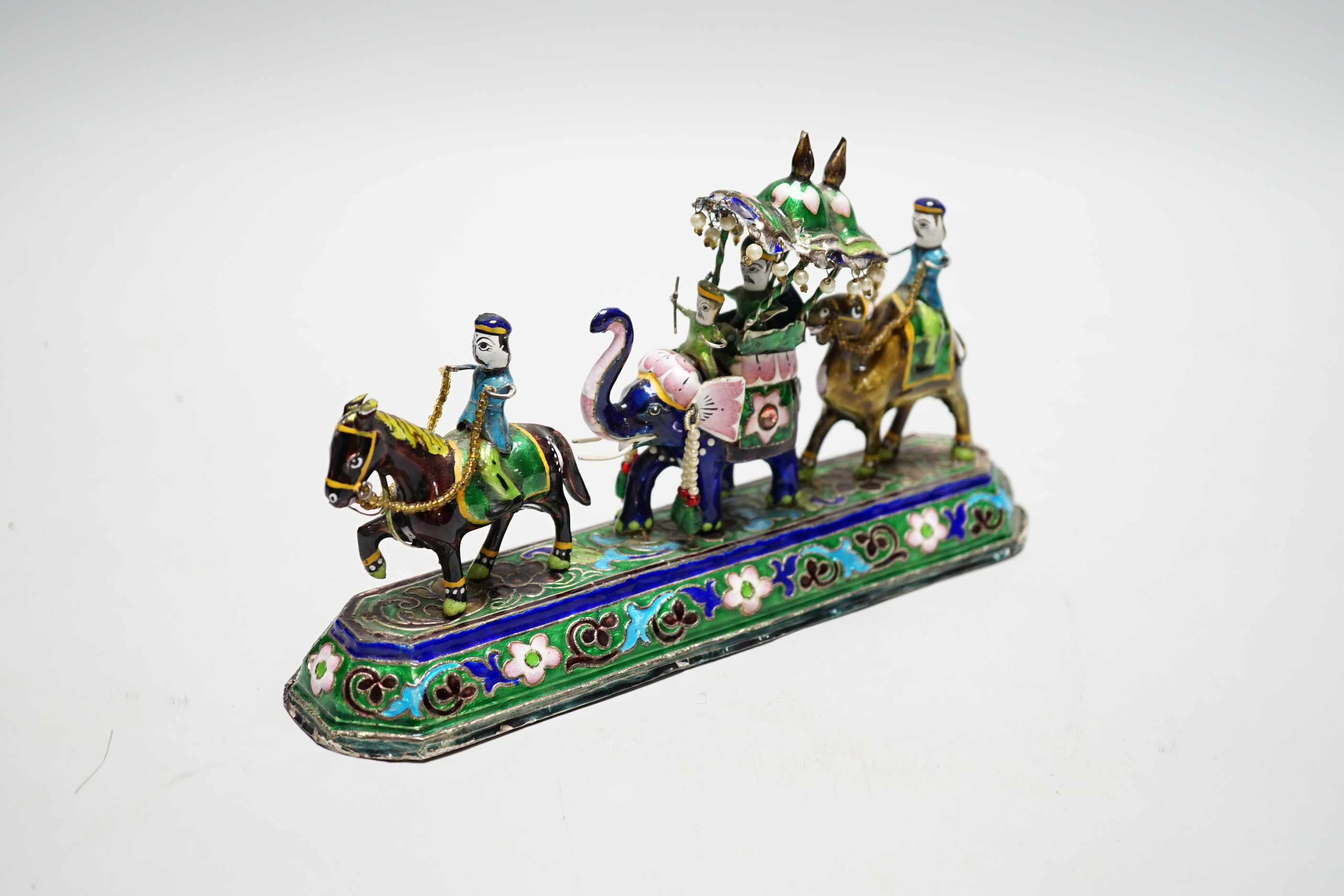 A 20th century Indian white metal and polychrome enamel figural group, with elephants and figures, stamped to base 'BHI SILVER', weighted, length 23cm.